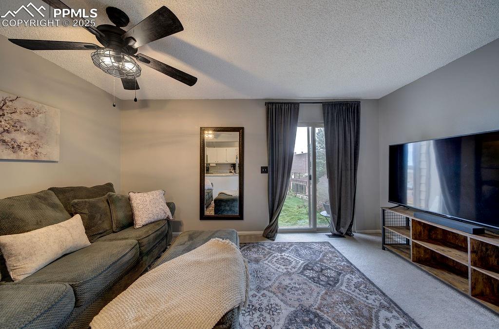 Image 15 of 48: Living area featuring a textured ceiling, carpet, and a ceiling fan