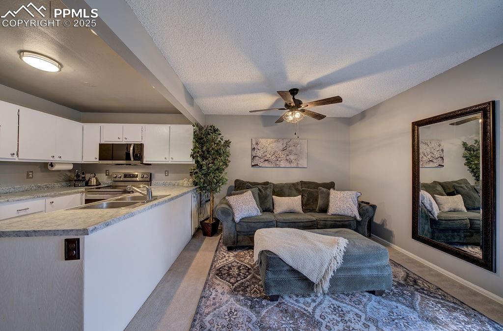 Image 18 of 48: Living room featuring a textured ceiling, beamed ceiling, a ceiling fan, an