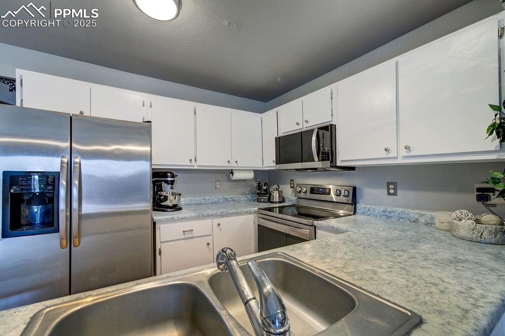 Image 21 of 48: Kitchen featuring appliances with stainless steel finishes, white cabinetry