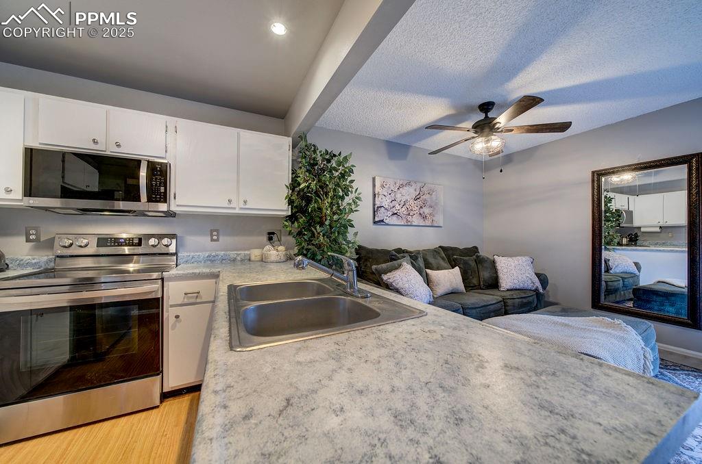 Image 22 of 48: Kitchen with appliances with stainless steel finishes, light countertops, w