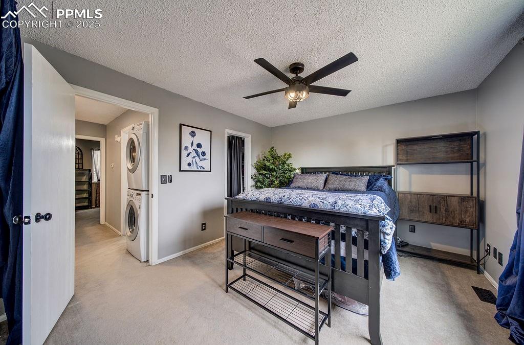 Image 27 of 48: Bedroom with stacked washer / drying machine, a textured ceiling, light car