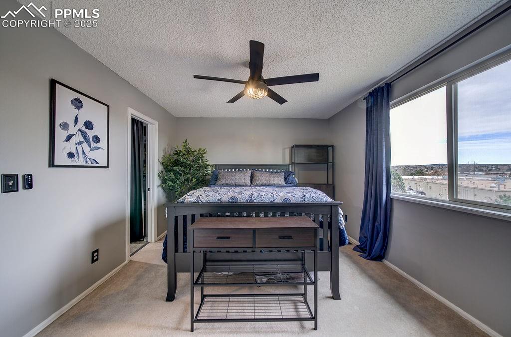 Image 28 of 48: Bedroom featuring a textured ceiling, light carpet, and a ceiling fan