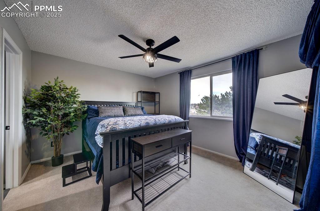Image 29 of 48: Bedroom with a textured ceiling, light carpet, and ceiling fan