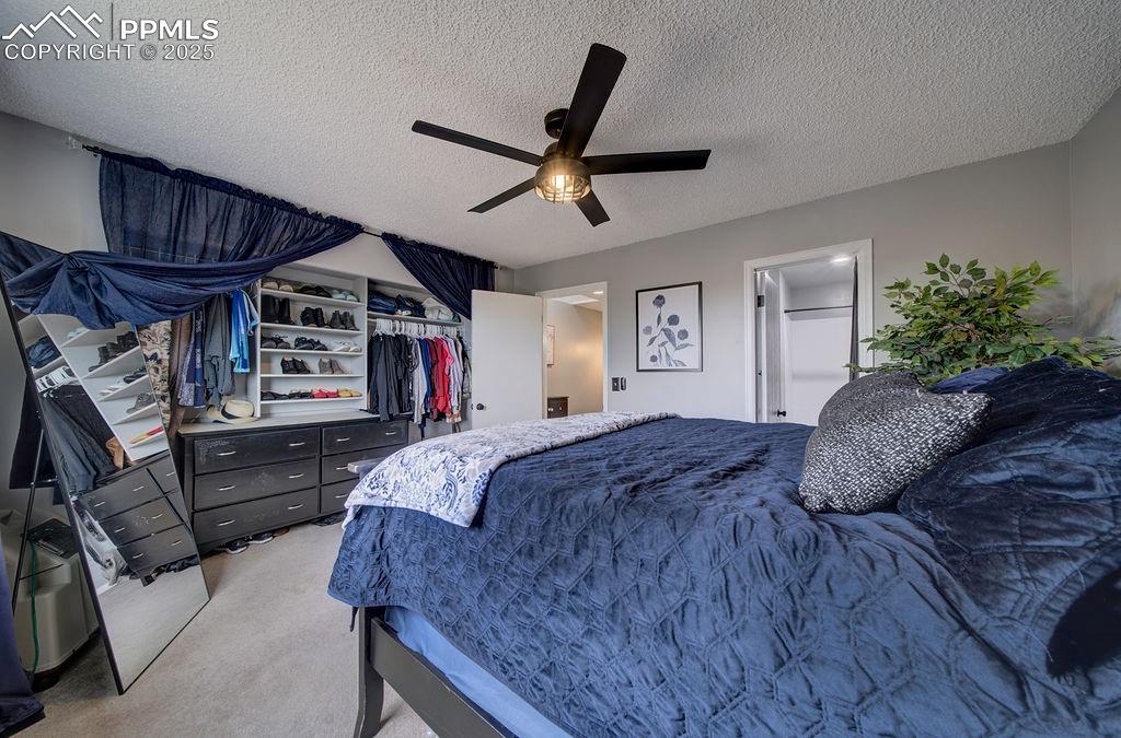 Image 30 of 48: Carpeted bedroom featuring a textured ceiling, ceiling fan, and a closet