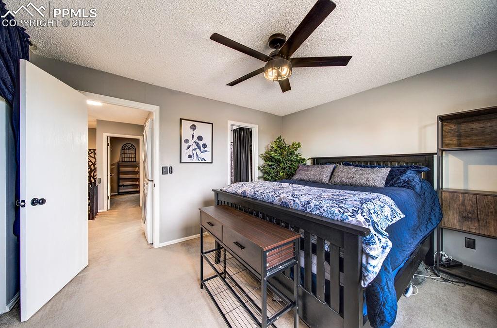 Image 31 of 48: Bedroom with a textured ceiling, light colored carpet, and a ceiling fan