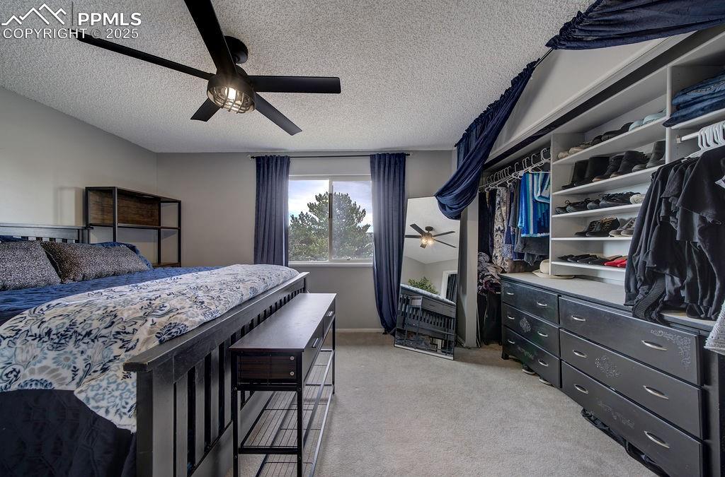 Image 32 of 48: Bedroom featuring light colored carpet, a textured ceiling, a ceiling fan, 