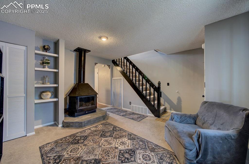 Image 42 of 48: Living room with stairway, light colored carpet, a textured ceiling, a wood
