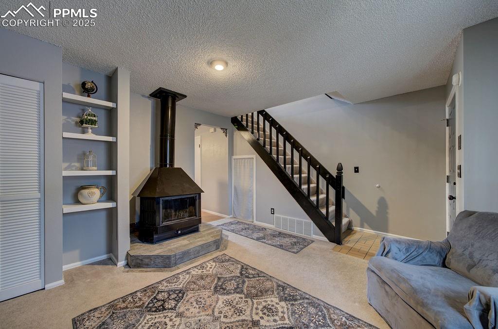 Image 9 of 48: Living room featuring light colored carpet, a textured ceiling, built in sh