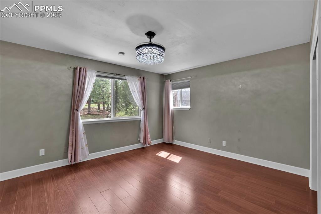 Image 35 of 49: Spare room with baseboards, a notable chandelier, and wood finished floors