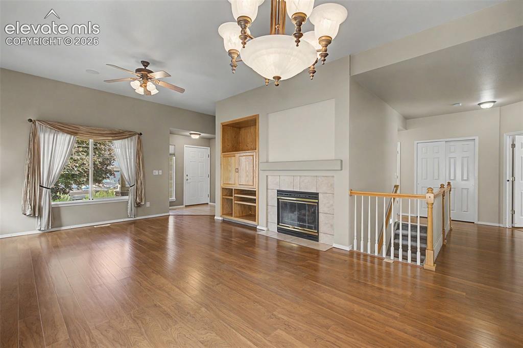 Image 12 of 49: Spacious common area featuring wood-finish flooring, a fireplace with a til