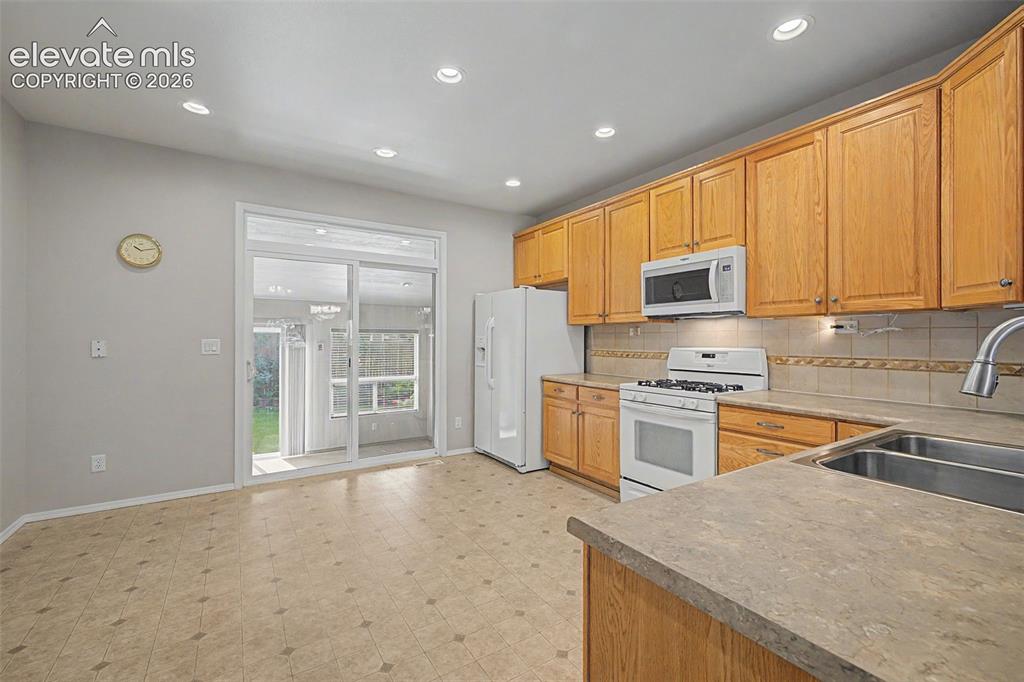 Image 16 of 49: Kitchen featuring wood cabinetry, laminate countertops, a tile backsplash,