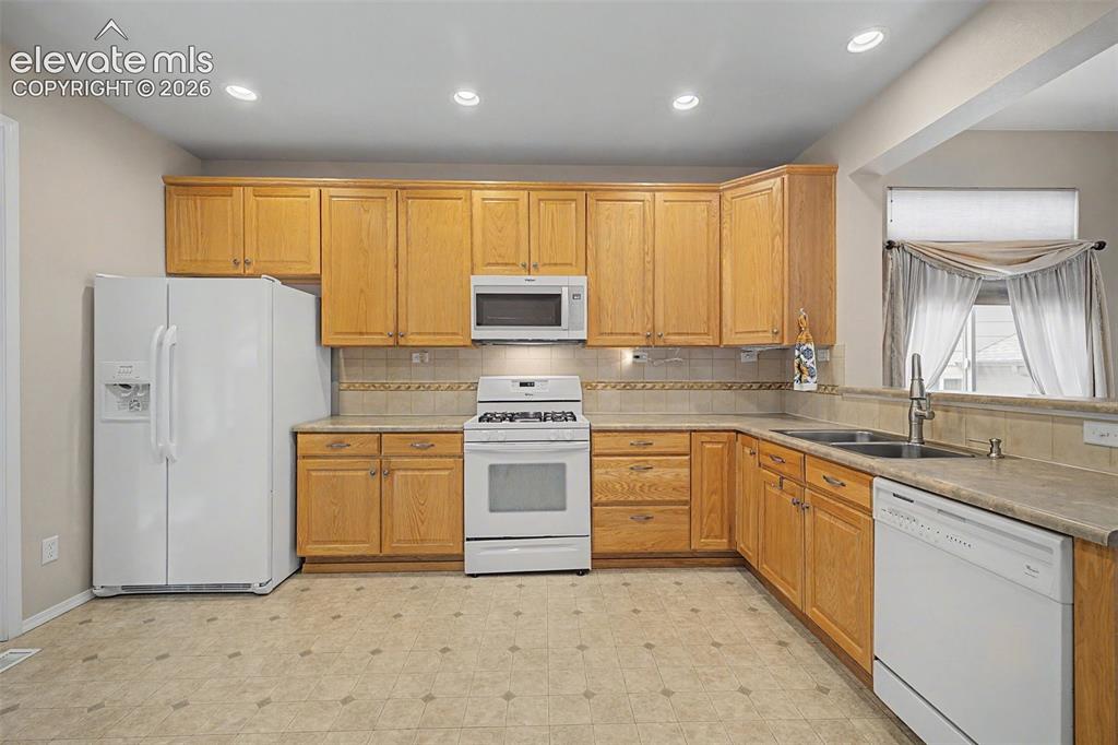 Image 17 of 49: Kitchen featuring light wood cabinetry, stone-finish countertops, and a ful