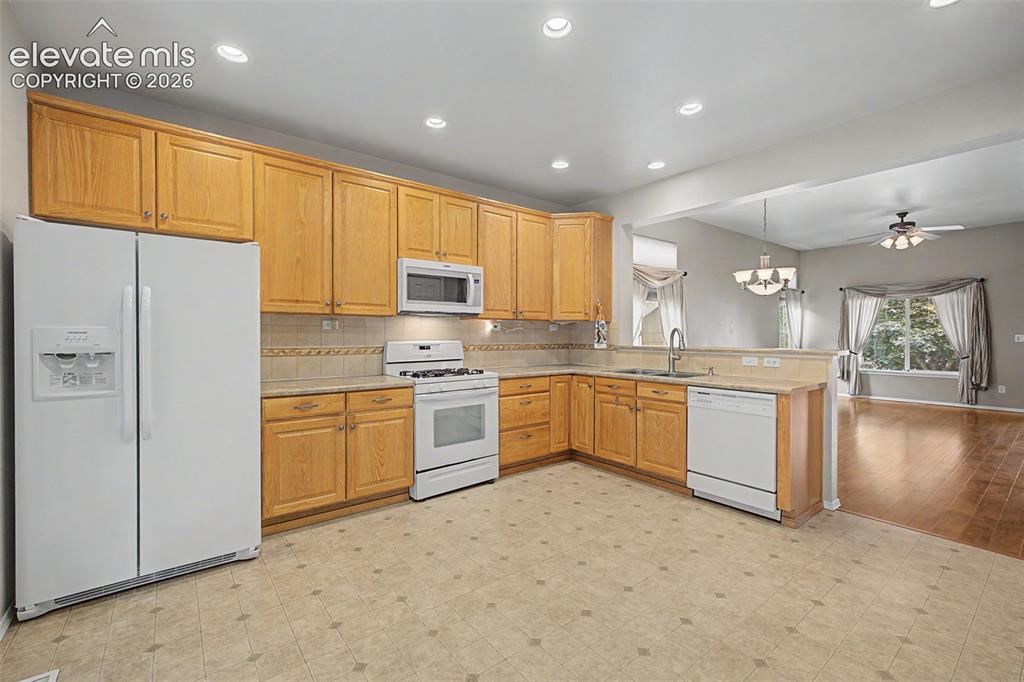 Image 18 of 49: Kitchen featuring wood cabinetry, a tile backsplash, white appliances, rece