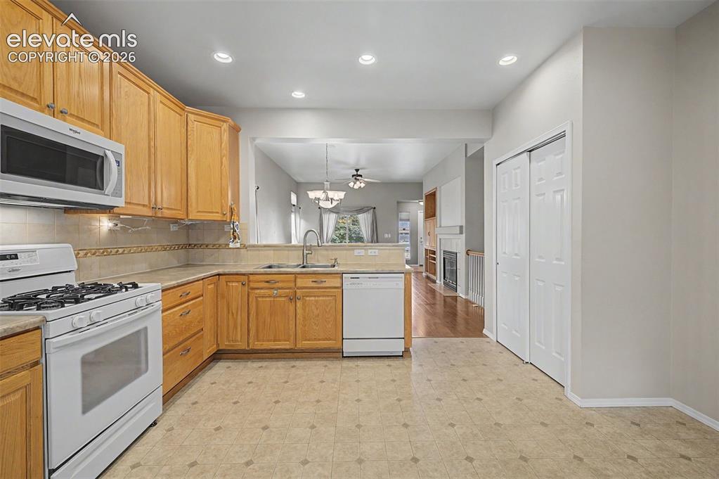 Image 19 of 49: Kitchen featuring wood cabinetry, white appliances, recessed lighting, and