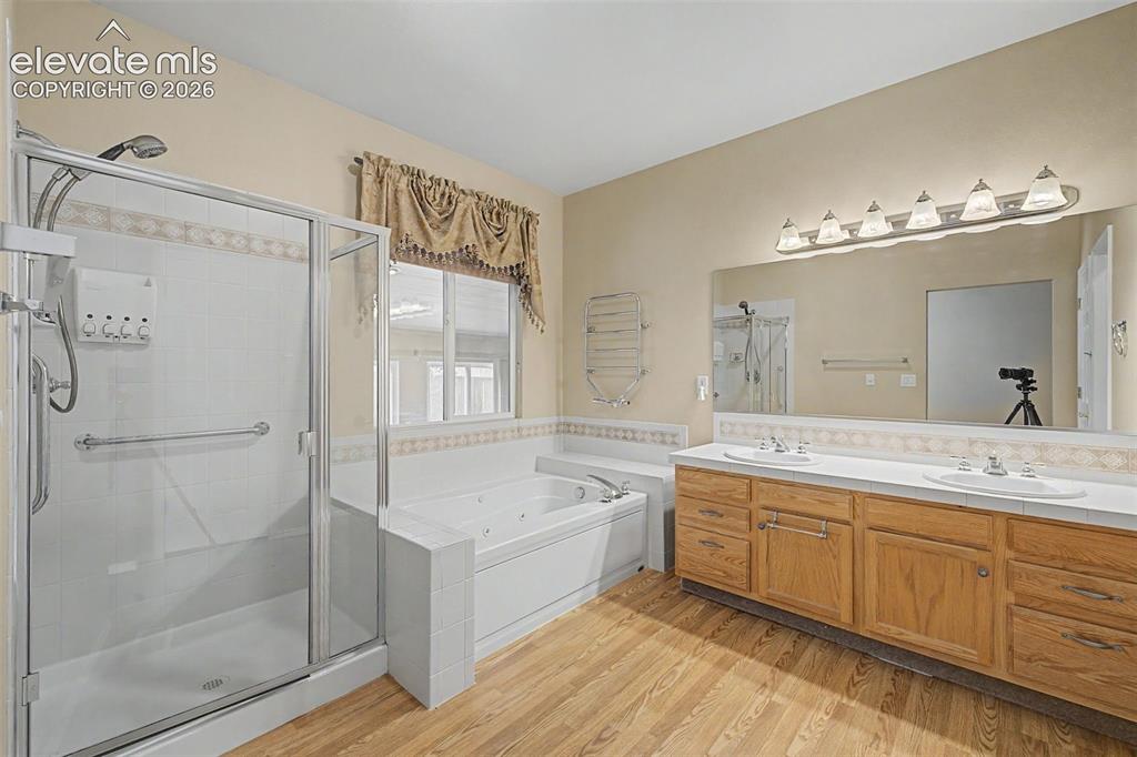 Image 27 of 49: Bathroom featuring a glass-enclosed shower, a built-in jetted tub, a dual v