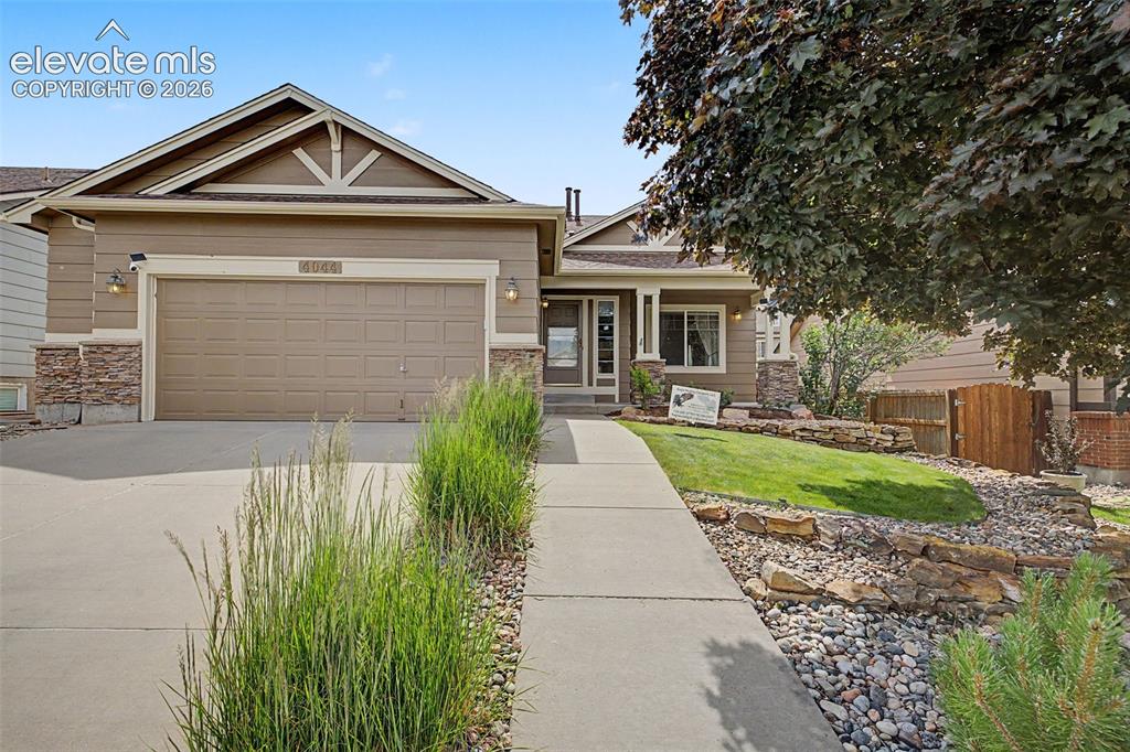 Image 4 of 49: Ranch-style exterior with a two-car garage, stone accents, and a covered fr
