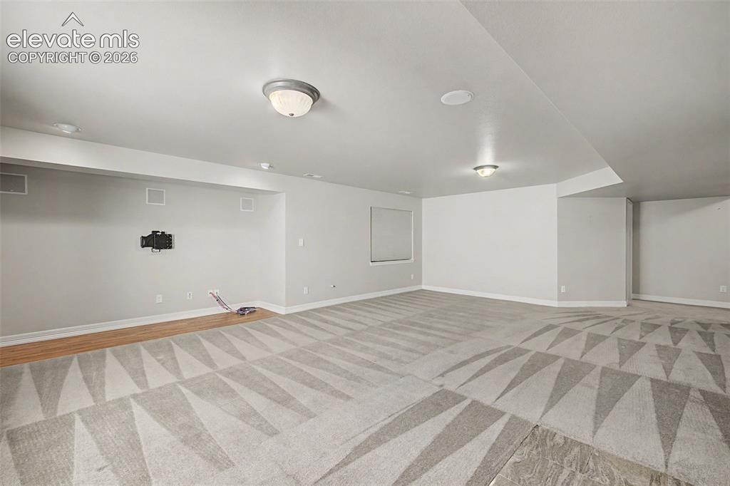 Image 42 of 49: Spacious room featuring patterned carpet flooring, a wood-finish flooring s