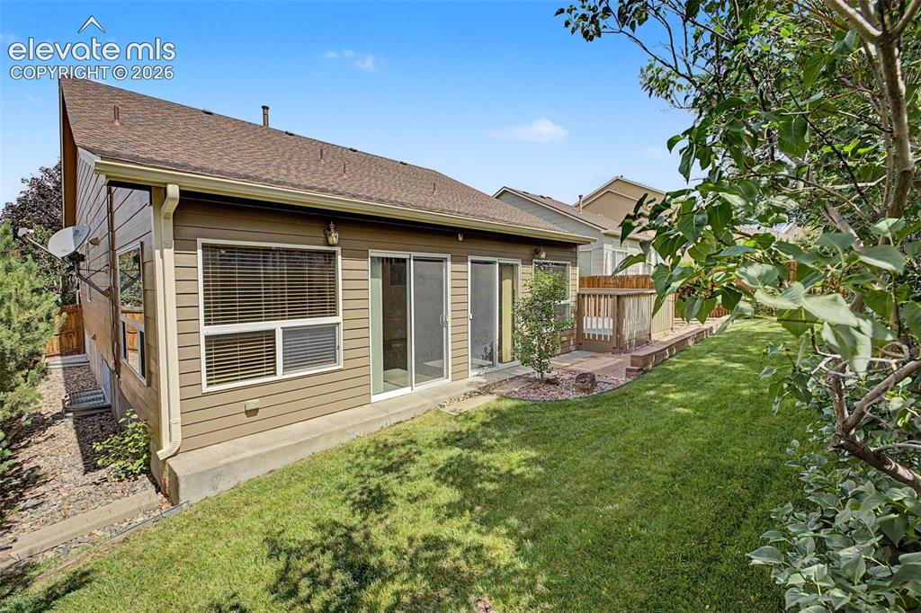 Image 48 of 49: Rear exterior featuring tan horizontal siding, a brown shingle roof, a slid