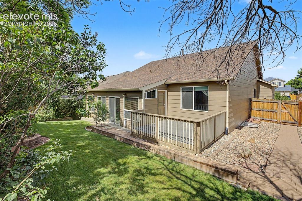 Image 49 of 49: Expansive backyard featuring a manicured lawn, a wood deck with railings, a