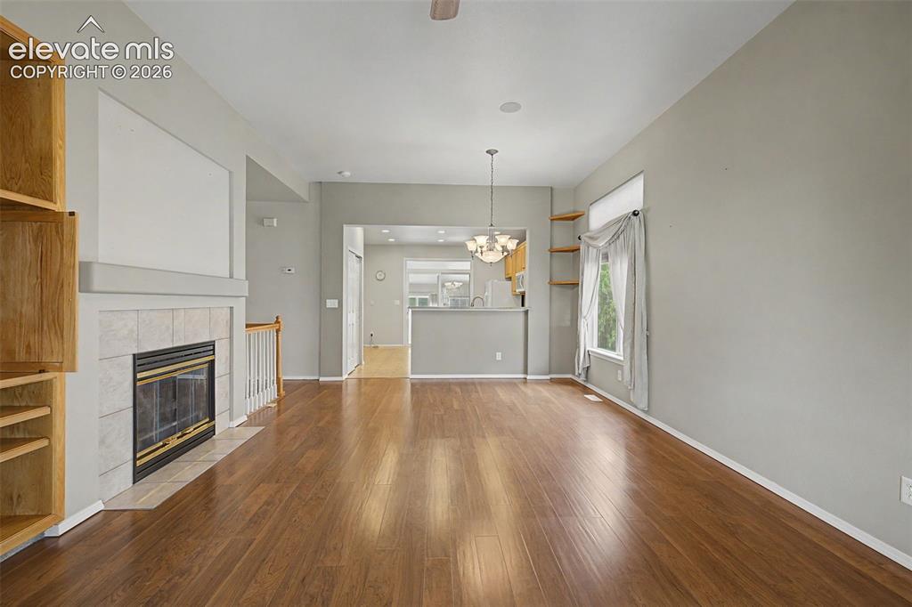 Image 6 of 49: Spacious living area featuring wood-finish flooring, a tiled fireplace with