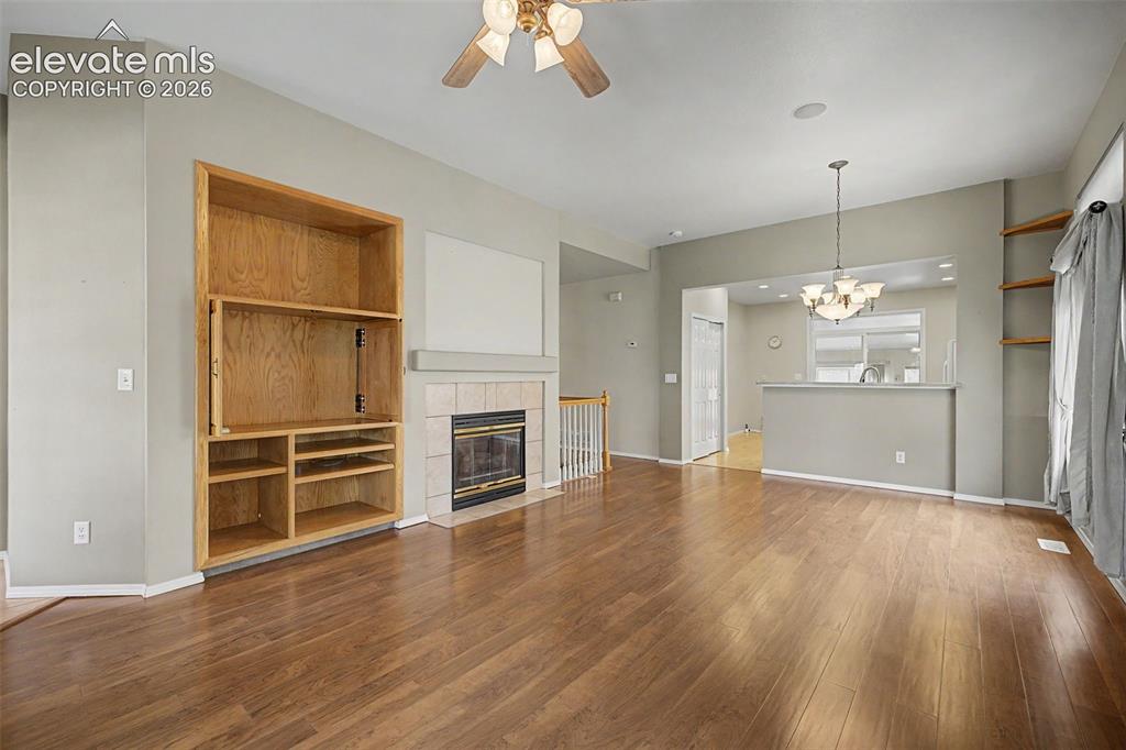 Image 8 of 49: Spacious living area featuring wood-finish flooring, a built-in media cabin