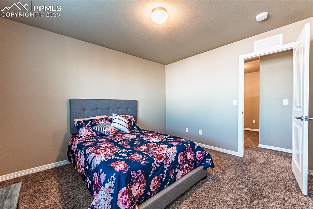 Image 22 of 46: Carpeted bedroom with visible vents, baseboards, and a textured ceiling