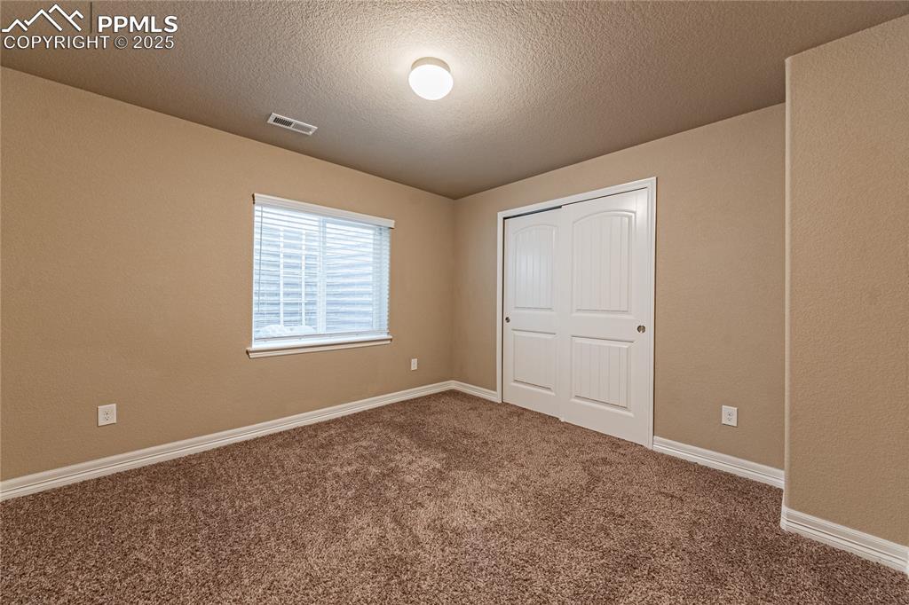 Image 39 of 46: Unfurnished bedroom with a closet, baseboards, carpet flooring, a textured