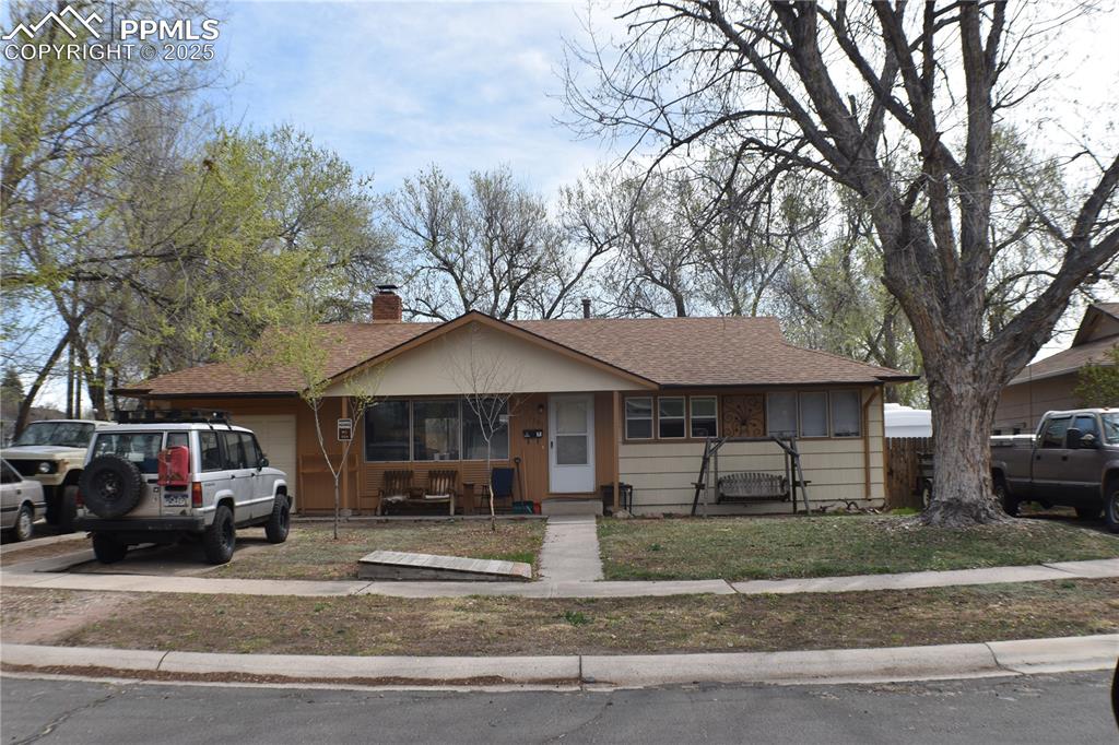 Caption: View of front of house with a shingled roof, a garage, and a chimney