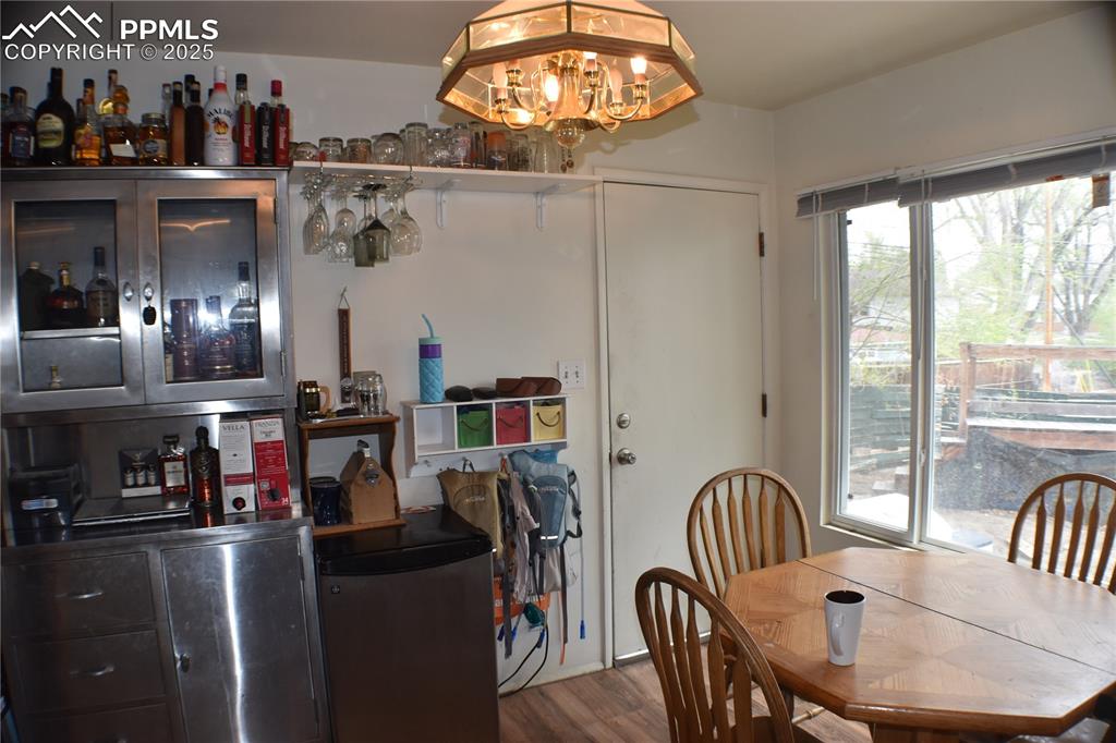 Image 10 of 31: Dining room with wood finished floors, a bar, and an inviting chandelier