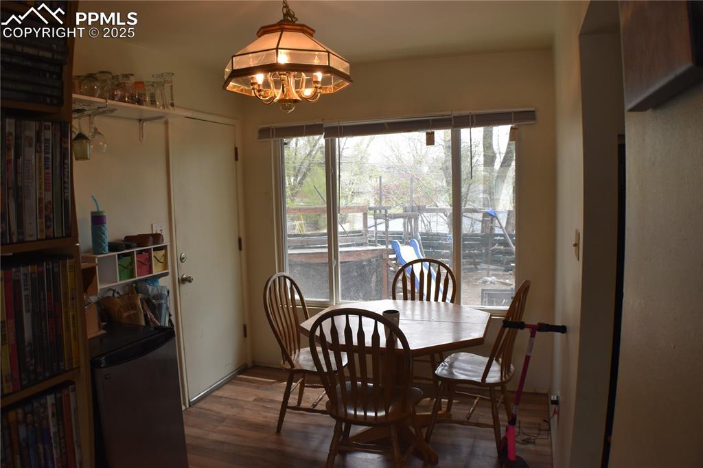 Image 11 of 31: Dining area with wood finished floors and an inviting chandelier