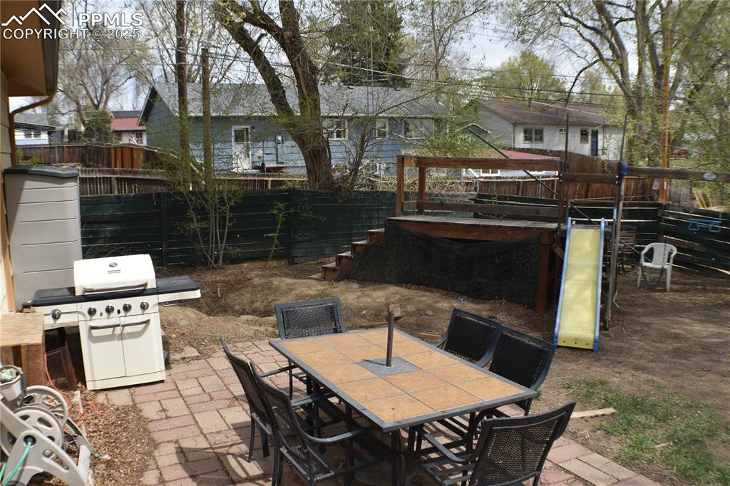 Image 21 of 31: View of patio with outdoor dining space, area for grilling, fence, and a pl