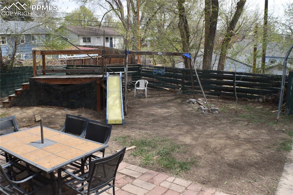 Image 22 of 31: View of yard featuring outdoor dining area, fence, a patio area, and a play