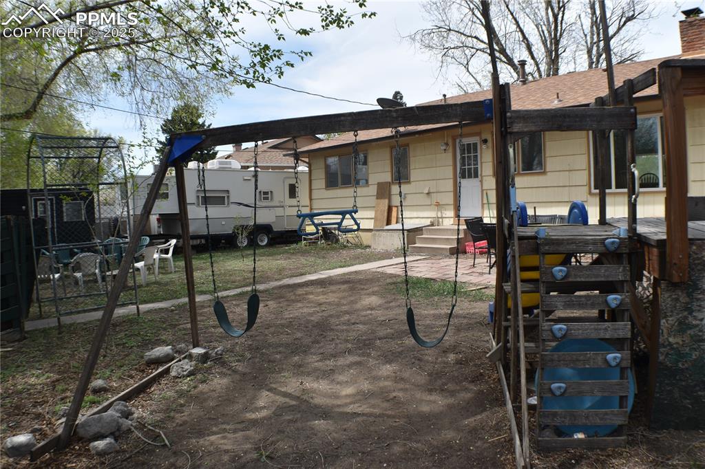 Image 26 of 31: Rear view of property featuring a chimney, a playground, entry steps, and a
