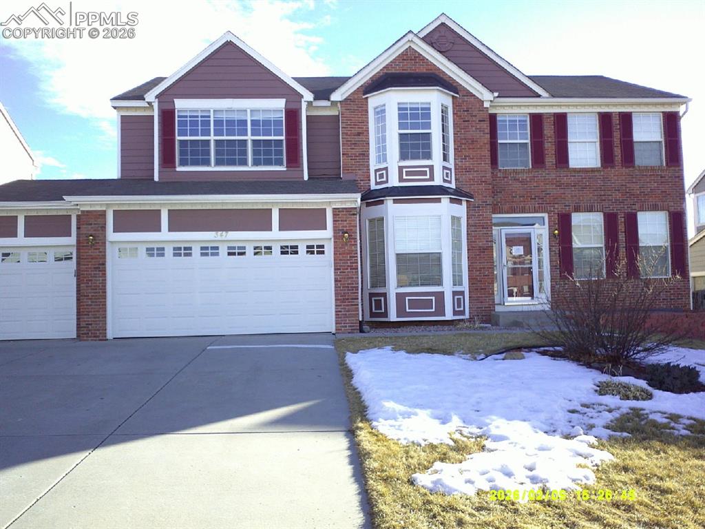 Image 1 of 21: View of front facade featuring driveway, a garage, and brick siding