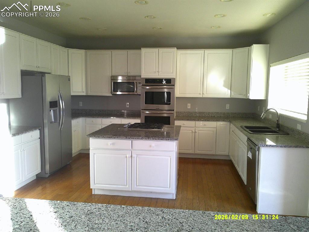 Image 7 of 21: Kitchen featuring white cabinetry, dark stone countertops, stainless steel 