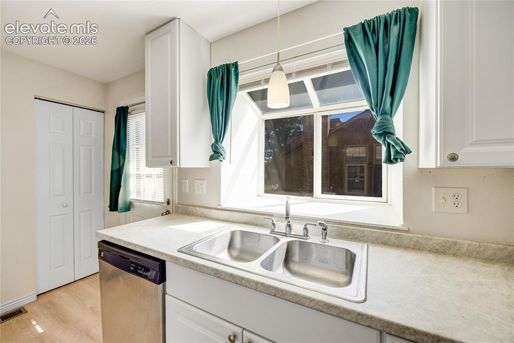 Image 13 of 27: White cabinetry, stainless steel sink, light-toned countertops, stainless s