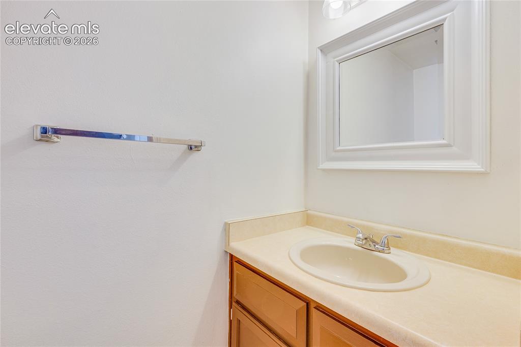 Image 14 of 27: Vanity with an integrated sink, dual-handle faucet, wood-finish cabinetry, 