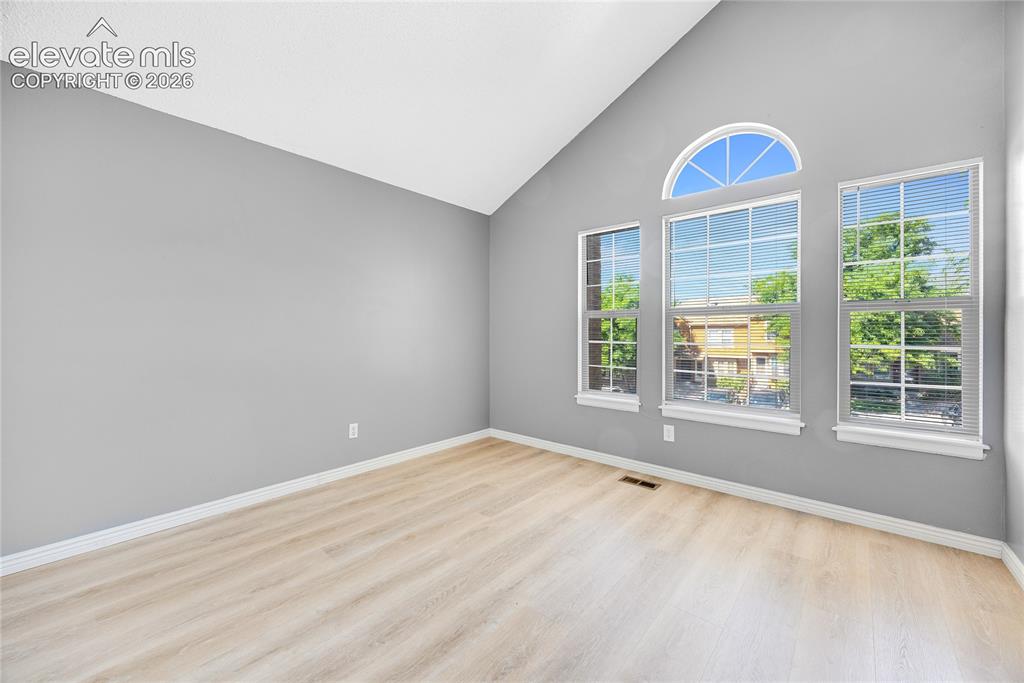 Image 19 of 27: Vaulted ceiling, light-toned wood-finish flooring, multiple windows, arched