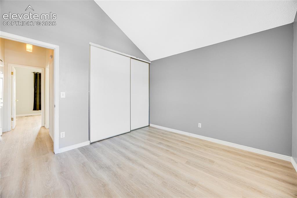 Image 20 of 27: Vaulted ceiling, wood-finish flooring, sliding closet doors, and light gray