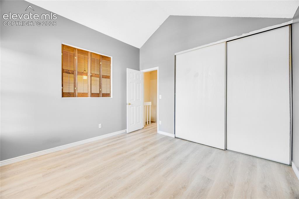 Image 21 of 27: Vaulted ceiling, light wood-finish flooring, warm gray wall finish, window 