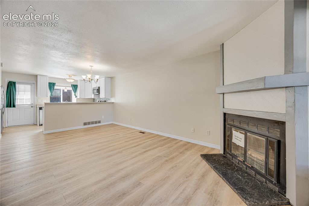 Image 5 of 27: Light wood-finish flooring throughout, featuring a fireplace with a dark st