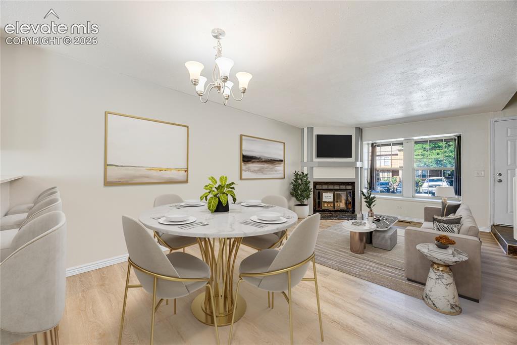 Image 6 of 27: Open-concept living area featuring wood-finish flooring, a white fireplace