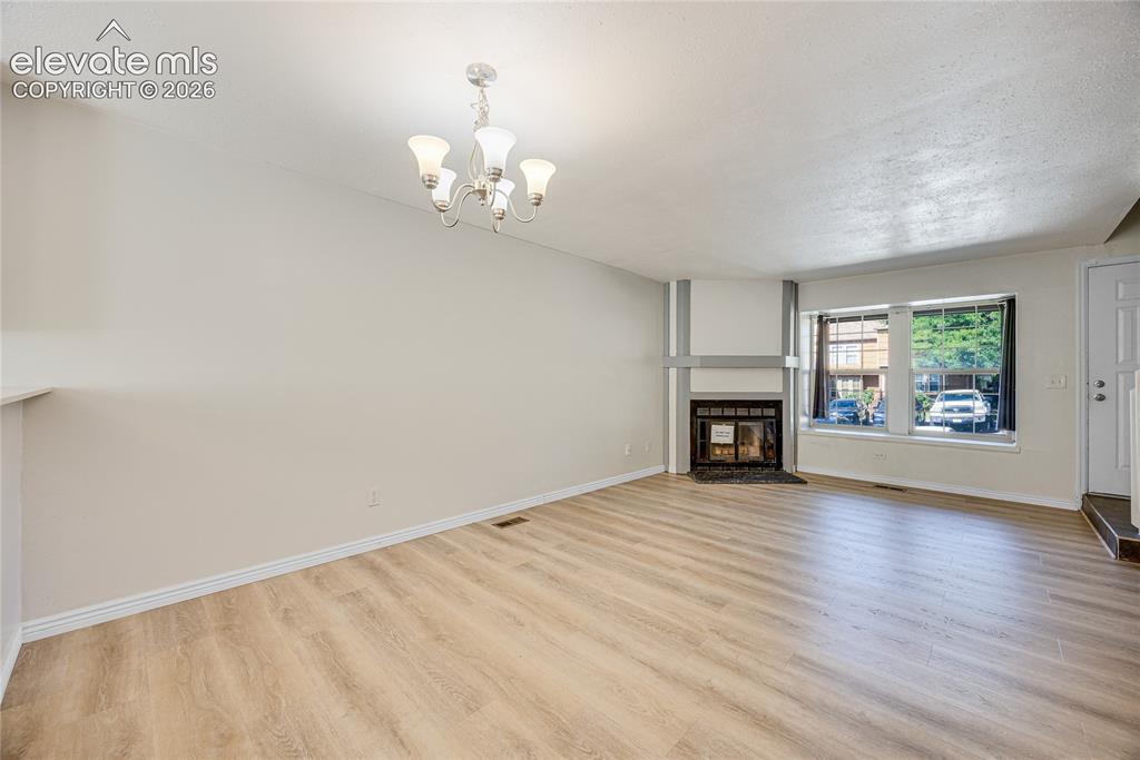 Image 7 of 27: Spacious room featuring wood-finish flooring, a built-in fireplace with a h