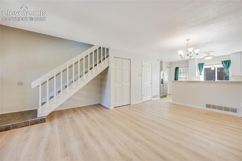 Image 9 of 27: Light wood-finish flooring throughout, white painted staircase, and white i