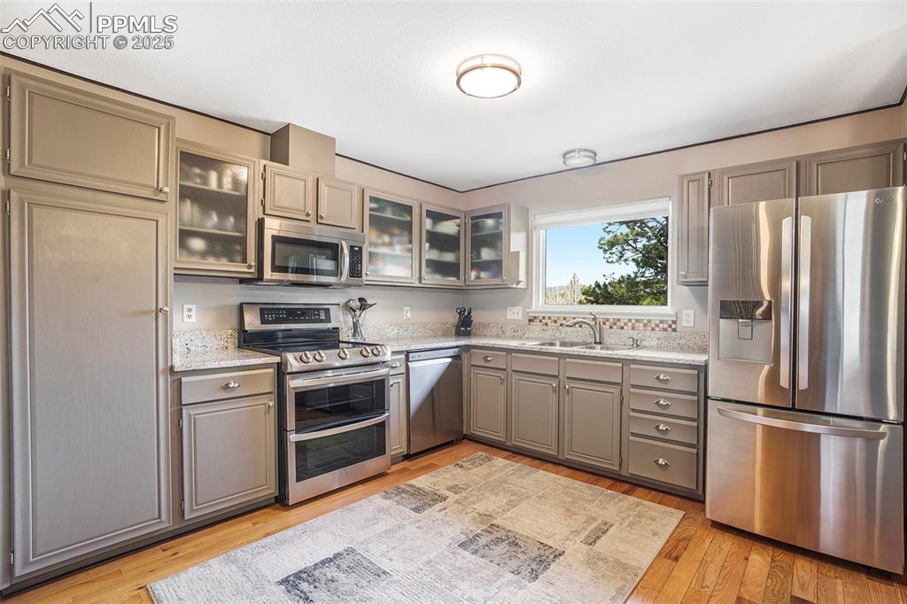 Image 9 of 29: Kitchen featuring light wood finished floors, stainless steel appliances, a