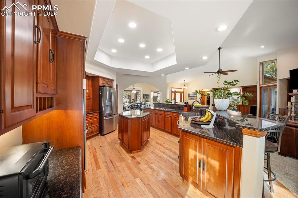 Image 11 of 48: Kitchen with a kitchen breakfast bar, dark stone countertops, open floor pl