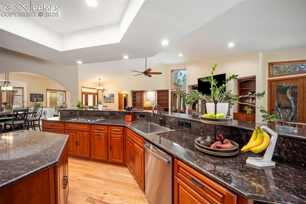 Image 13 of 48: Kitchen with arched walkways, dark stone countertops, brown cabinets, a cha
