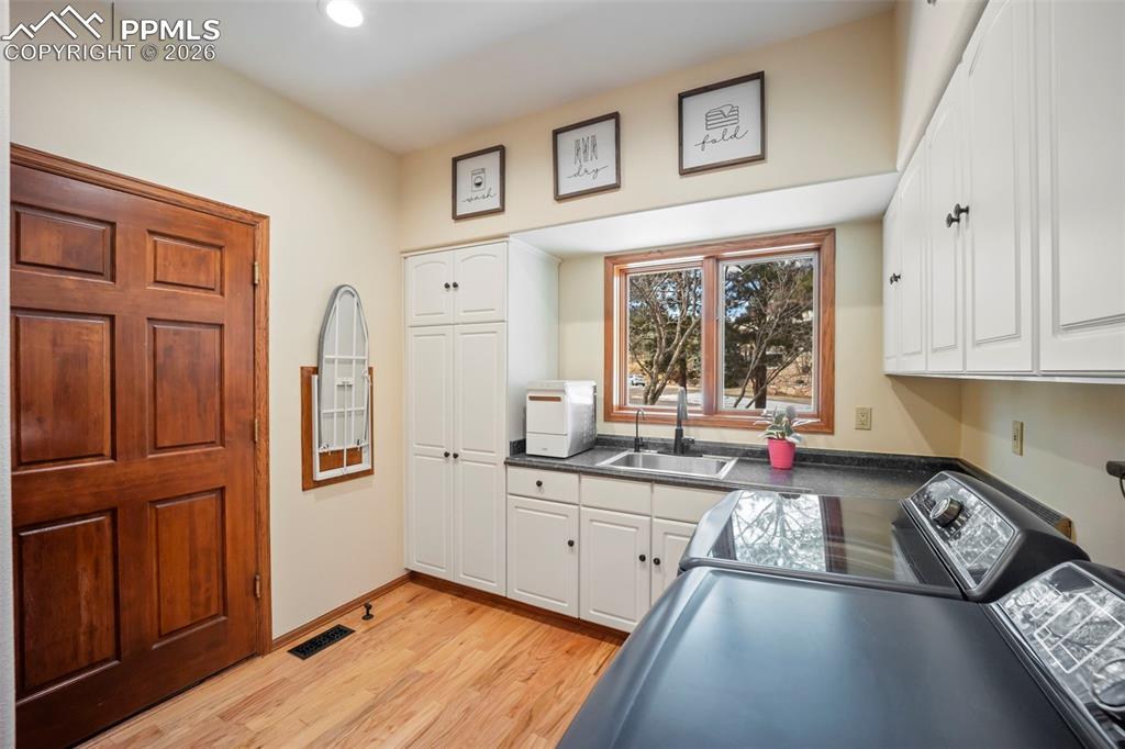 Image 19 of 48: Laundry room featuring cabinet space, hardwood floors, and washing machine 