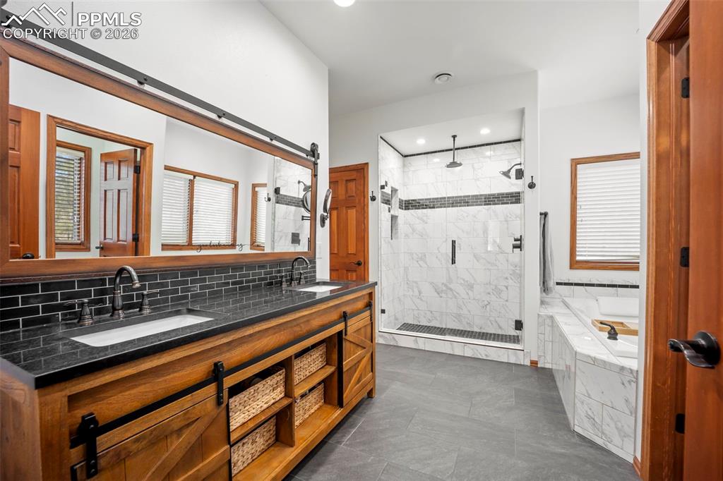 Image 22 of 48: Full bath with heated floor, double vanity, a shower stall, a bathtub, and 