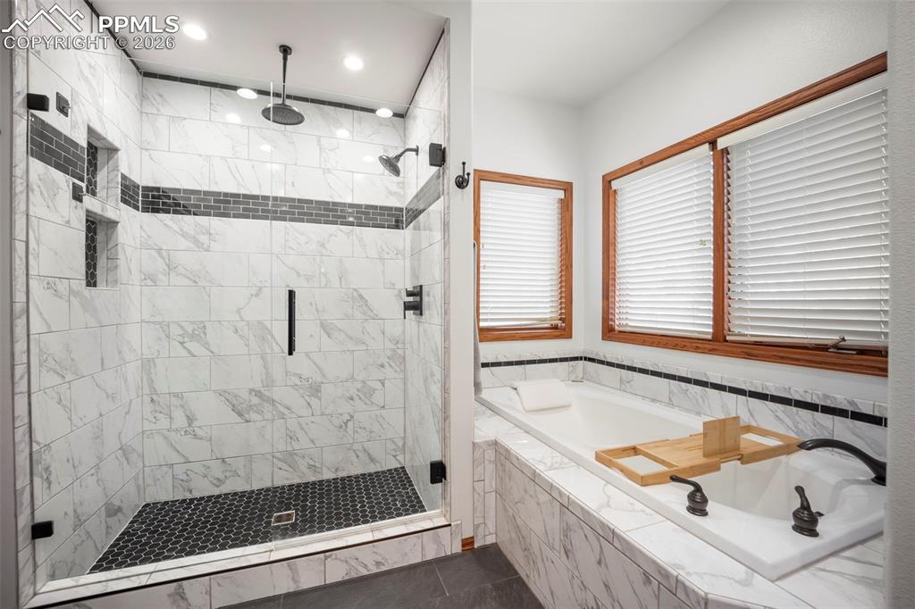 Image 23 of 48: Full bathroom featuring a heated floor, bathtub, a shower stall, and dark t